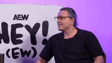 a man stands in front of a sign that says aew