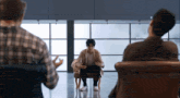 a man in a wheelchair is sitting in a chair talking to two other men