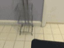 a shadow of a chair is cast on the tiled floor