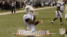 a football player is catching a ball on a field in front of a sign that says tough town .