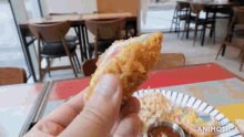 a person is holding a piece of fried food in front of a plate of food that says made in animatica