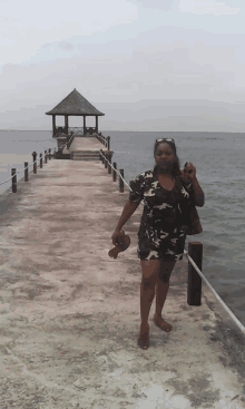 a woman standing on a dock with a gazebo in the distance