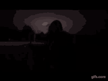 a silhouette of a person standing in the dark with a light behind them .