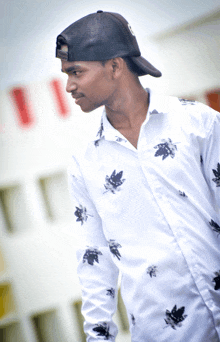 a young man wearing a white shirt with black leaves on it