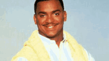 a man wearing a yellow vest and a white shirt is smiling for the camera .