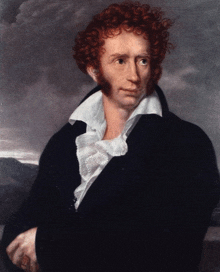 a man with red curly hair is wearing a black jacket and white shirt