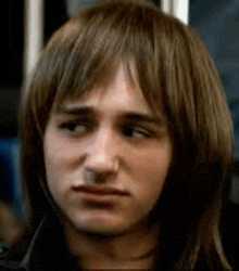 a close up of a man 's face with long hair and a wig on .