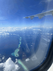 an airplane window shows the wing of a plane flying over the ocean