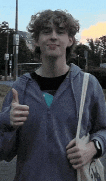 a young man is giving a thumbs up sign