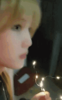 a little girl holding a string of lights in her hands