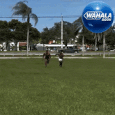 two people running in a field with a balloon that says wahala rock on it