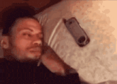 a man is laying on a bed holding a cell phone .
