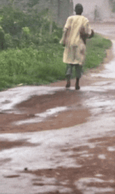 a person in a yellow shirt is walking down a wet road