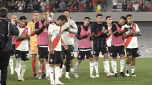 a group of soccer players are standing on a field with one wearing a shirt that says ' river plate ' on it