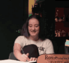 a woman is writing on a piece of paper in front of a box that says rosie