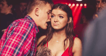 a man in a plaid shirt is kissing a woman in a red dress