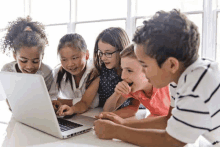 a group of young children are looking at a laptop computer .