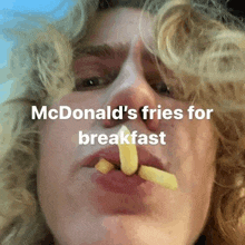 a man with curly hair is eating french fries from mcdonald 's for breakfast