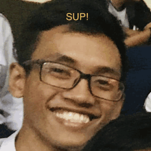 a man wearing glasses is smiling with the word sup above him