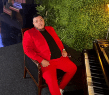 a man in a red suit is sitting in a chair next to a piano