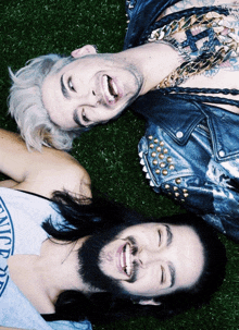 two men are laying on the grass with one wearing a tank top that says california