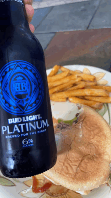 a bottle of bud light platinum next to a hamburger and french fries