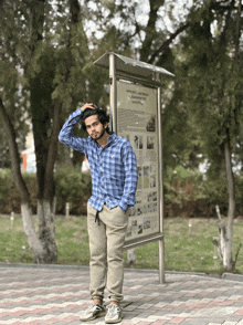 a man in a blue plaid shirt stands in front of a sign that says ' a ' on it in russian