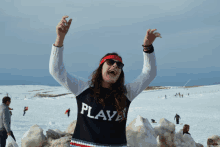 a woman wearing a sweater that says play is standing in the snow