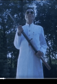 a man in a white coat and sunglasses holds a rifle