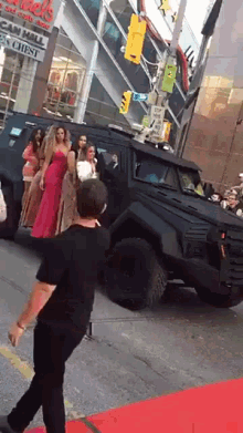 a group of women are standing on a red carpet in front of a building that says cad 's car mall