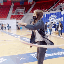 a woman is playing with a hula hoop on a basketball court in front of a sign that says " annual group 2019 "