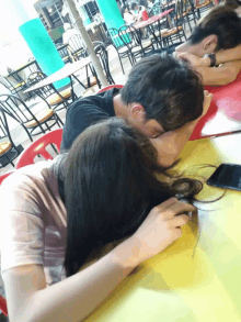 a man and a woman are sitting at a table with their heads together