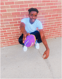 a young man squatting down holding a purple frisbee that says ssd