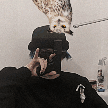 a man taking a picture of himself with an owl hanging over his head