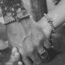 a man and a woman holding hands with bracelets on