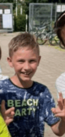 a boy wearing a beach party shirt is smiling and giving a thumbs up