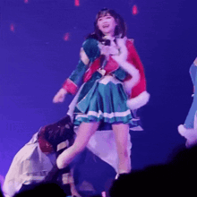 a woman in a green and red dress is standing on a stage