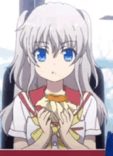 a girl with gray hair and blue eyes is sitting at a table holding a banana .