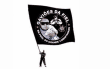 a man holding a black flag that says gavioes da fiel on it