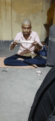 a man is sitting on the floor eating a plate of food