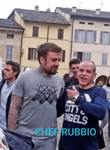 a man wearing a shirt that says city angels is standing next to another man