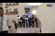 a man stands at a podium with microphones in front of a sign that says ' riyadh '