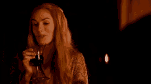 a woman is drinking a glass of wine in the dark .