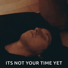 a man laying on the floor with the words " it 's not your time yet " below him