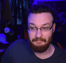 a man with a beard wearing glasses looks at the camera