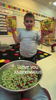 a young boy is holding a bag of sour patch kids candy and a bowl of candy .