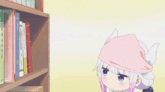 a girl with a pink hat is standing in front of a bookshelf .
