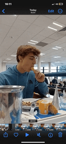 a phone screen shows a young man eating a snack and says today at the top