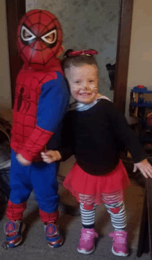 a boy in a spiderman costume stands next to a little girl