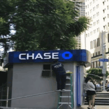 a man on a ladder works on a chase bank